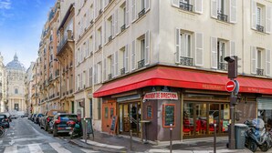 A street view with a restaurant named "BRASSERIE" with a red awning, parked cars, and a traffic light. - Appartement Grenelle - Welkeys (Paris)