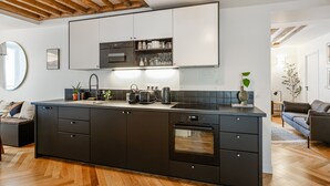 A modern kitchen with a large island, built-in appliances, and a wooden ceiling. - Appartement Grenelle - Welkeys (Paris)