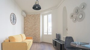 Una sala moderna con un sofá, una mesa de comedor con sillas, un televisor y decoración en la pared.