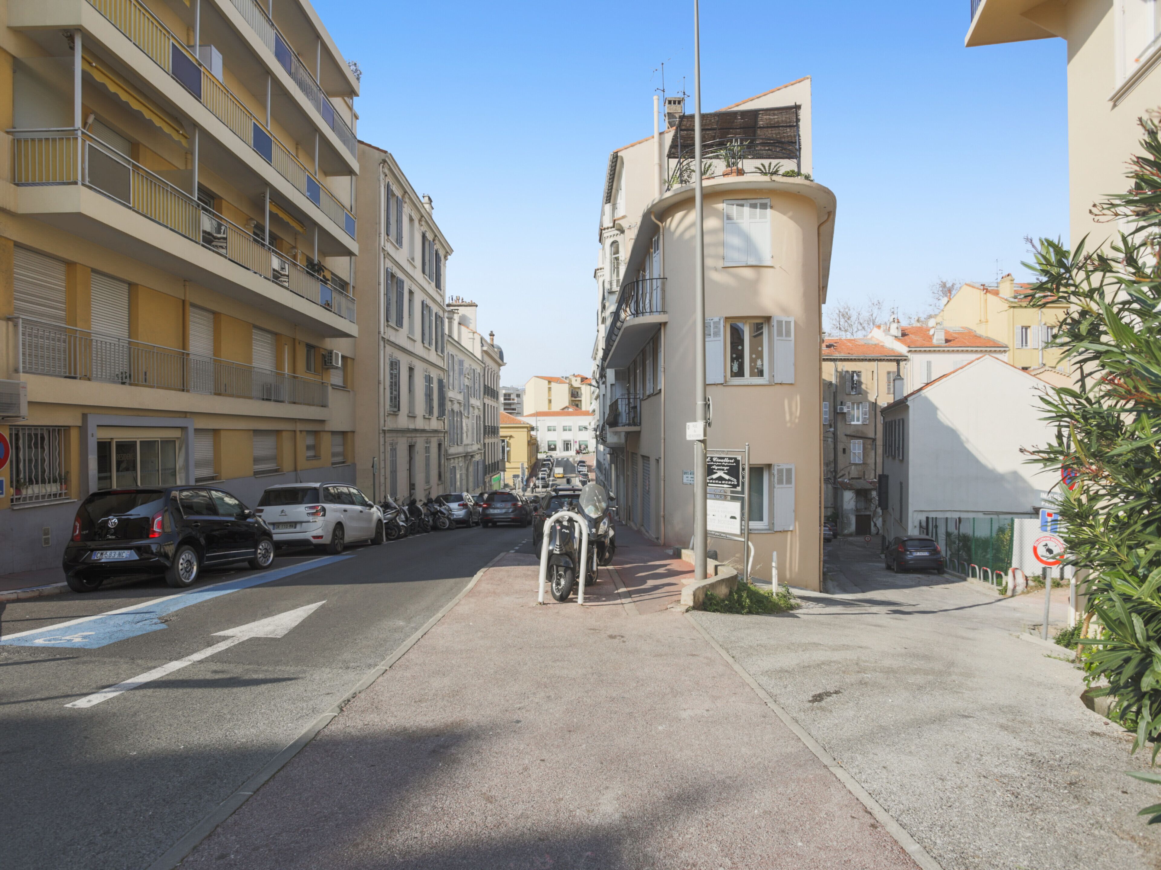 Una calle con coches estacionados y un edificio de fachada curva.