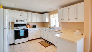 A kitchen with white cabinets, a microwave, stove, and a sink. - Beachfront Old Orchard Beach Condo w/ Balcony (Old Orchard Beach)