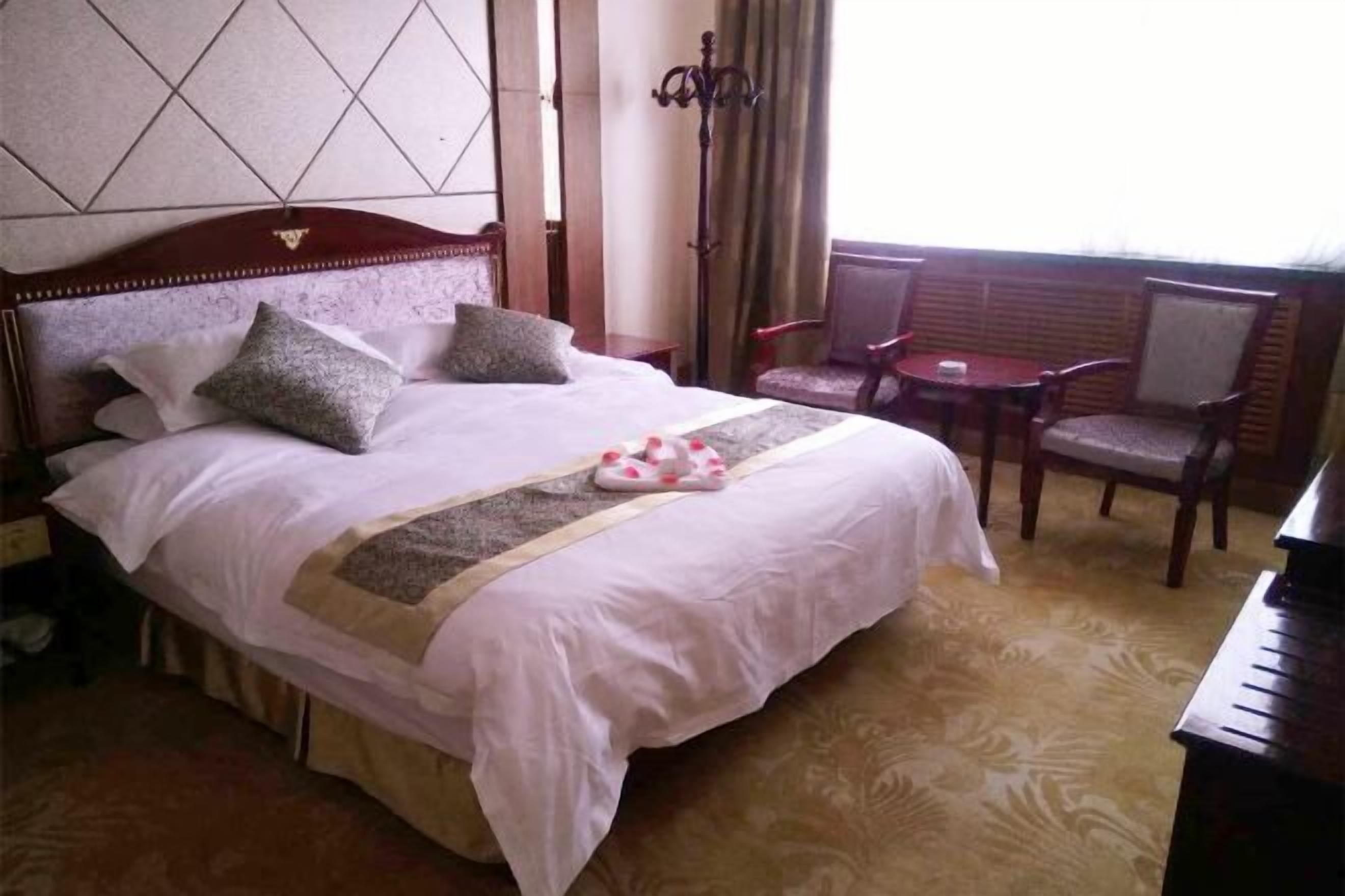 A hotel room with a large bed, a small table, and a chair.