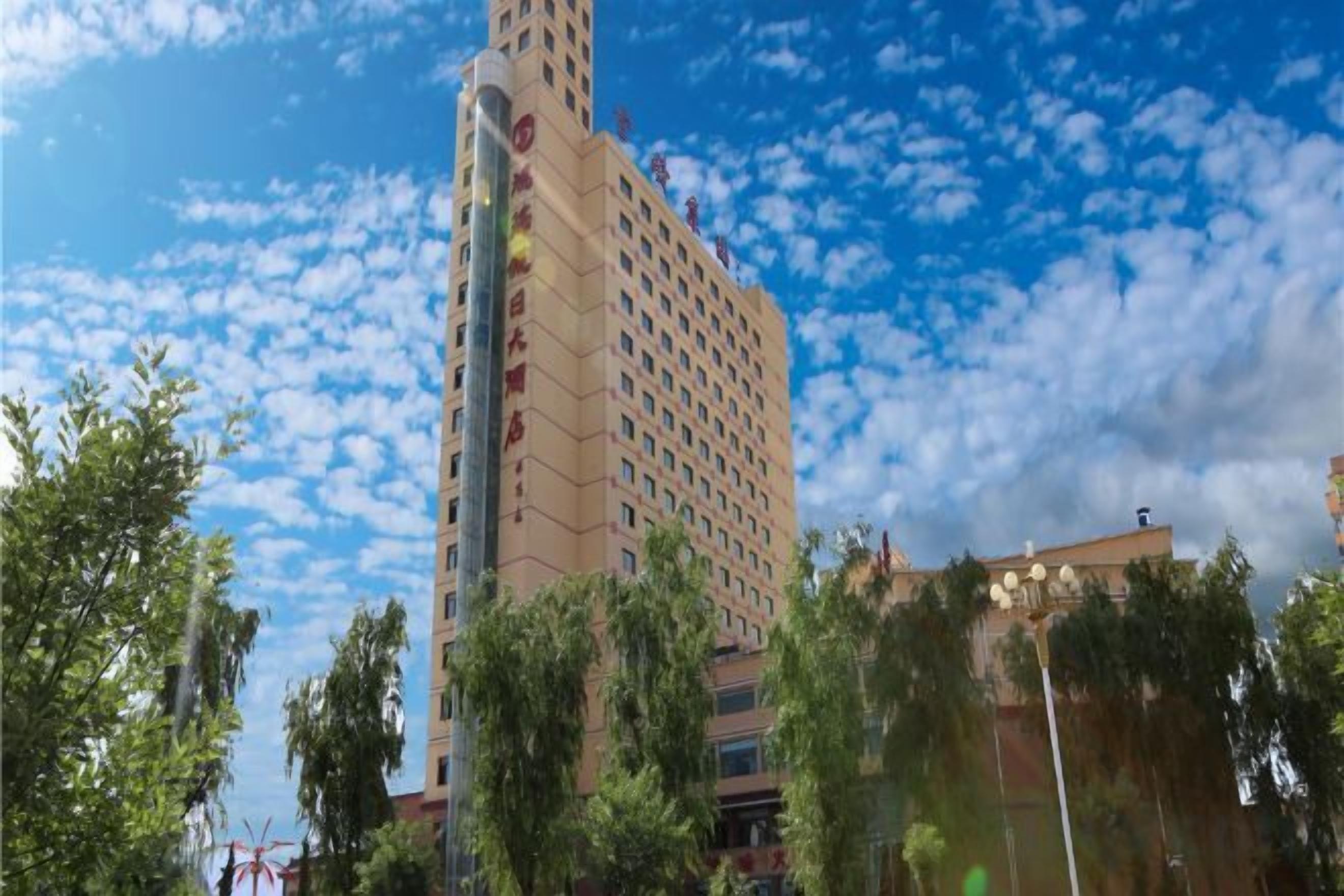 Ein mehrstöckiges Hotel mit markant vertikaler Gestaltung, umgeben von Bäumen und unter leicht bewölktem Himmel.