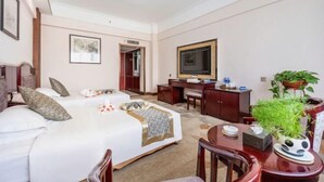 Habitación de hotel con cama, escritorio, silla, televisor y planta en maceta.