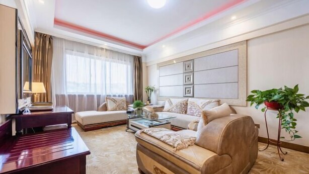 Una habitación de hotel con sofá, escritorio, mesa de centro y un amplio ventanal con cortinas.