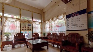 A traditional-style lobby with wooden furniture, large windows with floral curtains, and informational posters on the walls. - Huifeng Hotel (Shaoguan)