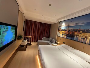 A hotel room with a large bed, a TV on the wall, a desk, and a view of a cityscape. - Huifeng Hotel (Shaoguan)