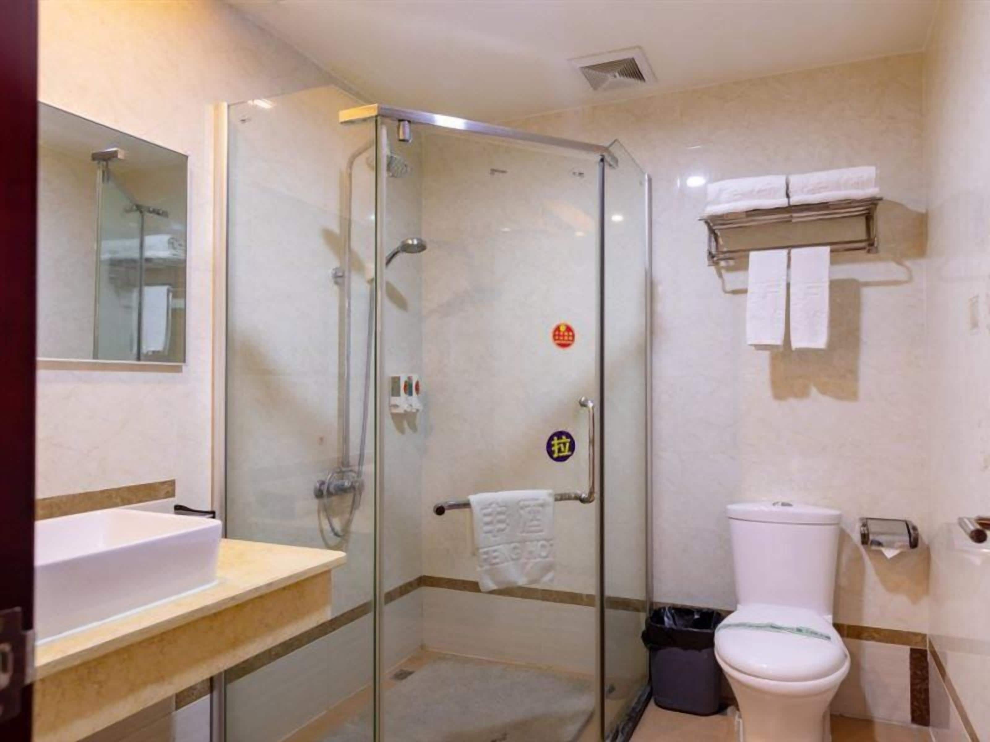 A modern bathroom with a glass-enclosed shower, a sink, and a toilet.