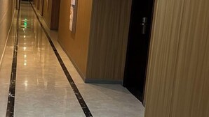 A hallway with a polished floor, wooden doors, and a green exit sign. - Huifeng Hotel (Lechang)