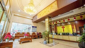 A hotel lobby with wooden furniture, a reception desk, and a chandelier. - Huifeng Hotel (Lechang)