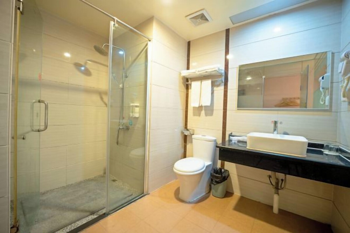 A modern bathroom with a glass shower enclosure, a toilet, a sink, and a mirror.