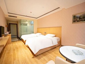 A hotel room with a bed, bedside table, and a small table with a chair. - Huifeng Hotel (Shaoguan)