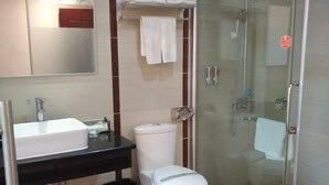 A bathroom with a white sink, black countertop, white toilet, and a glass shower enclosure. - Huifeng Hotel (Shaoguan)