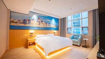 A hotel room with a large bed, a nightstand, a chair, a TV, and a painting of a cityscape.