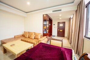 A living room with a sofa, a coffee table, and a red blanket. - Huifeng Hotel (Shaoguan)