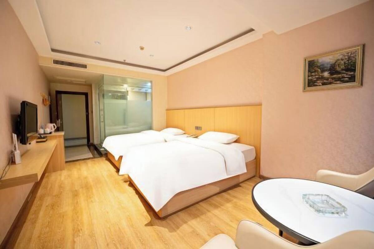 A hotel room with a bed, a desk, a chair, and a small table.