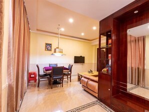 A hotel room with a dining area, a sofa, a TV, and a wooden cabinet. - Huifeng Hotel (Shaoguan)