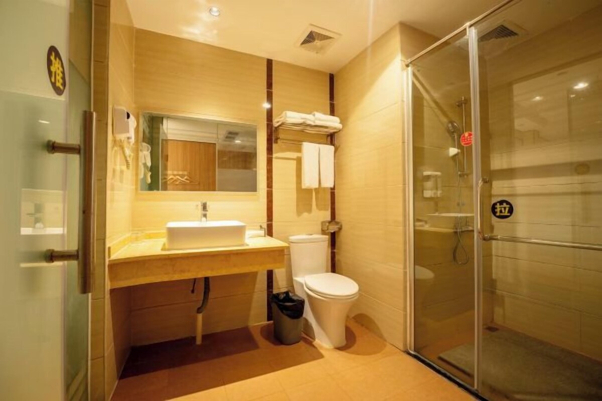A modern bathroom with a glass shower enclosure, a sink with a mirror, and a toilet.
