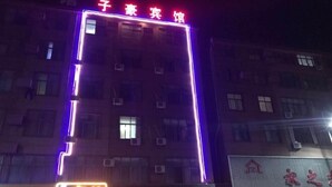 A building with illuminated signage, including a prominent red sign at the top and a neon sign below. - Guzhen Zihao Hotel (Guzhen)