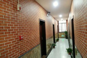 A corridor with brick walls, doors, potted plants, and a tiled floor. - Guzhen Zihao Hotel (Guzhen)