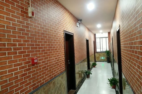 A corridor with brick walls, doors, potted plants, and a tiled floor.. Guzhen Zihao Hotel