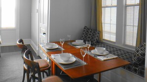 A dining room with a wooden table set for four, chairs, and a bench with cushions. - Downtown Victorian Flat Great Location and free Parking (Chattanooga)