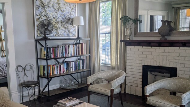 A living room with a sofa, armchairs, a fireplace, a bookshelf, and a fan. - Downtown Victorian Flat Great Location and free Parking (Chattanooga)