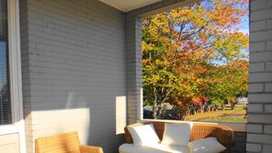 A covered outdoor seating area with wicker furniture and a glass table. - Downtown Victorian Flat Great Location and free Parking (Chattanooga)
