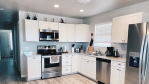 Una cocina moderna con armarios blancos, electrodomésticos de acero inoxidable y piso de madera.