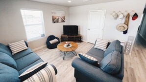 Una sala de estar moderna con un conjunto de sofá, una mesa de centro, un televisor y una puerta con un letrero.