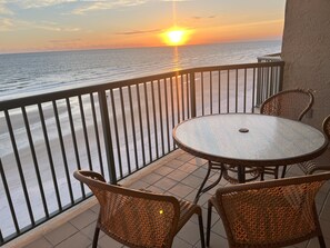 A balcony with a round table and wicker chairs, overlooking the ocean at sunset. - 🚨 BOOK NOW — Dates Going Fast! Private Oceanfront Penthouse, Ponce Inlet, FL (Ponce Inlet)