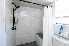 Ein Badezimmer mit Dusche, Toilette und einem Fenster.