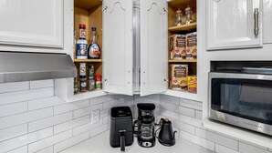 A kitchen with white cabinets, a coffee maker, a kettle, and a microwave. - Spacious 4BR Family Home, 6 Beds, Arcade, Game Room + Park Across Street (Watauga)