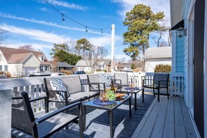 Eine überdachte Terrasse im Freien mit Sitzgelegenheiten und Tischen, umgeben von Häusern.
