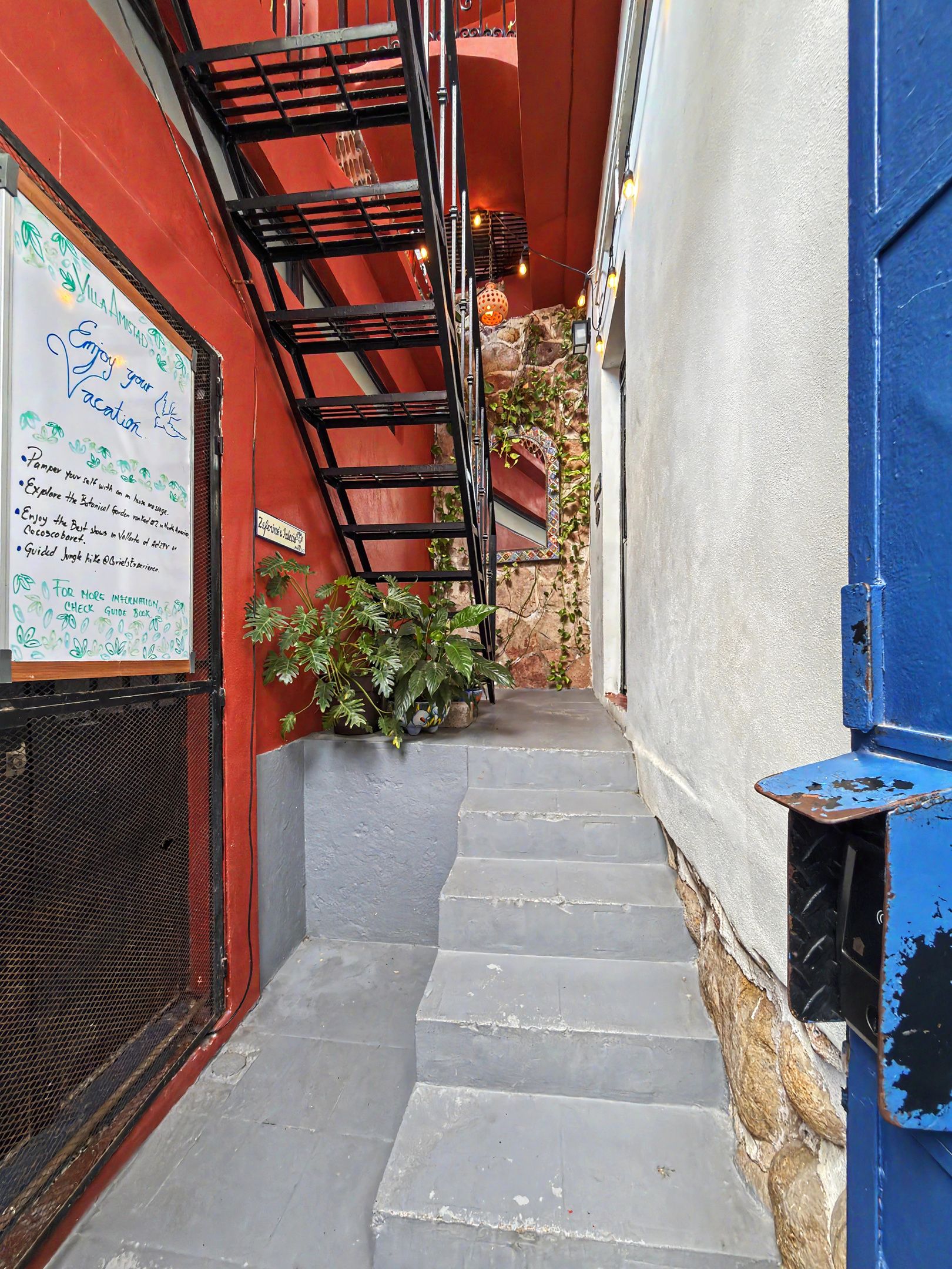 A narrow stairway leading to a building entrance with a signboard on the left.
