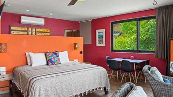 Une chambre à coucher comprenant un lit, un bureau, une chaise, une table et une fenêtre donnant sur un paysage verdoyant.