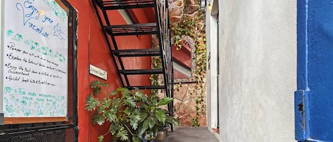 Una escalera estrecha que conduce a la entrada de un edificio, con un cartel a la izquierda.