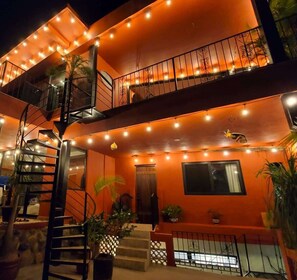A multi-story building with a spiral staircase, outdoor lighting, and potted plants.