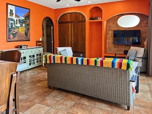 Una sala de estar con un sofá de mimbre, un televisor y un cuadro en la pared.