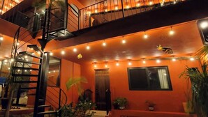 A multi-level building with a spiral staircase, outdoor string lights, and potted plants.