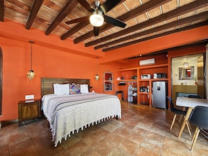 A room with a bed, a desk, a chair, a wardrobe, and a ceiling fan.