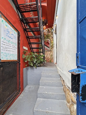 Una escalera estrecha que conduce a la entrada de un edificio, con un cartel a la izquierda.