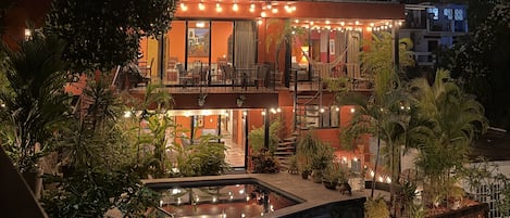 A multi-story building with outdoor seating and a pool area.