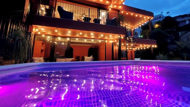 Et moderne hus med to etager og en swimmingpool i skumringen.