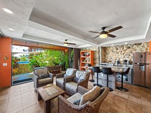 Un espacio habitable de concepto abierto con cocina, asientos exteriores y un ventilador de techo.