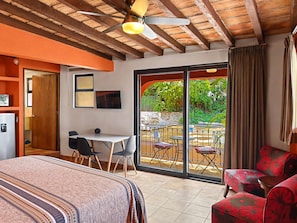 A hotel room with a bed, a desk, a chair, a table, and a balcony with outdoor seating. - Las Brisas: Main-Level 3BR, Private Terrace, Heated Pool, Walk to Malecón (Puerto Vallarta)