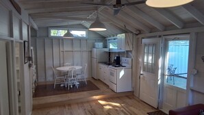 Une cuisine de taille réduite avec des meubles blancs, un réfrigérateur, une cuisinière et une table à manger avec des chaises.
