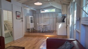 Un espace de vie compact comprenant un coin repas, une kitchenette et un escalier menant à un niveau supérieur.