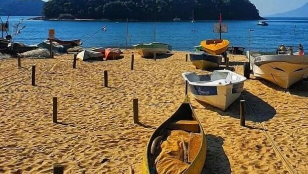 A sandy beach with several boats and a small island in the background. - Pousada Meraki Beach (Caraguatatuba)