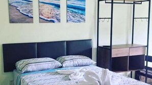 A neatly made bed with a patterned bedspread, a black headboard, and three paintings of the ocean on the wall. - Pousada Meraki Beach (Caraguatatuba)